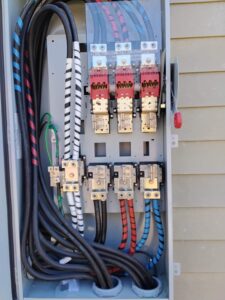 Close-up of a Dunkin’ store’s service equipment showing neatly routed service entrance conductors with color-coded phase markings, landed on main lugs inside the outdoor disconnect enclosure.