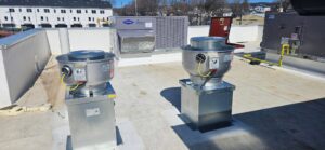 Rooftop of a Dunkin’ in Hackettstown featuring two newly installed commercial exhaust fans mounted on metal bases, with a Carrier HVAC unit and additional rooftop mechanical equipment visible in the background.