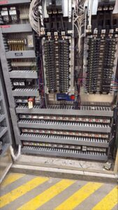 Open industrial control panel showing densely organized breakers, relays, terminal blocks, and wiring channels, with neatly routed conductors and labeled components throughout the enclosure.