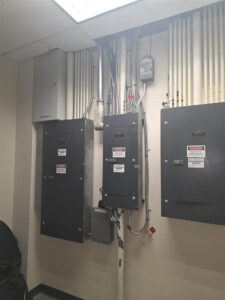 Electrical room with multiple switchgear panels and neatly organized vertical conduit runs mounted along the wall, showing completed commercial power distribution work.